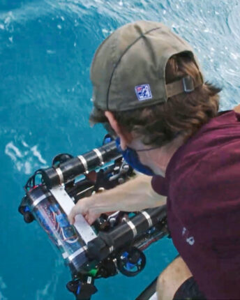 Researchers lowering a Reefgen device into the sea from a boat