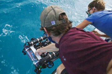 Researchers lowering a Reefgen device into the sea from a boat