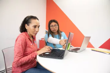 Woman being tutored on how to use the internet on a laptop