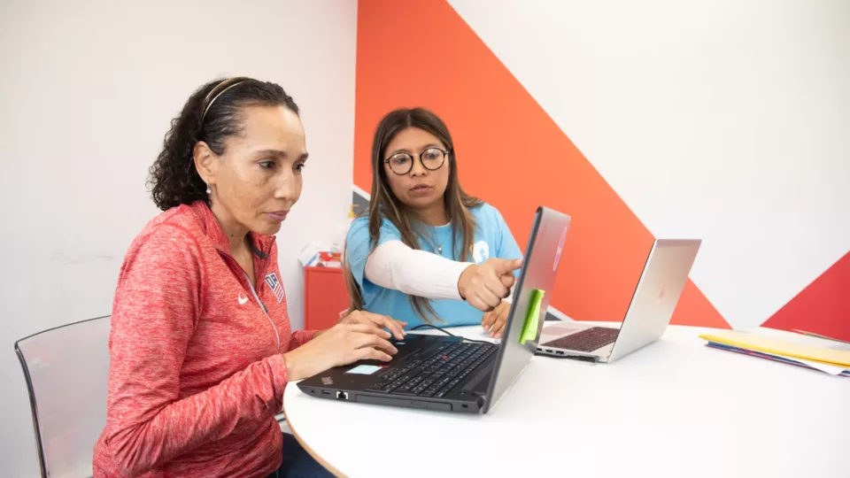 Woman being tutored on how to use the internet on a laptop