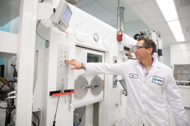 The head of Translational Imaging Biomarkers at Merck operating a machine that synthesizes alpha-synuclein tracers